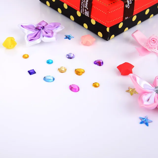 Gems, bows and ribbon rolls arranged on a white surface